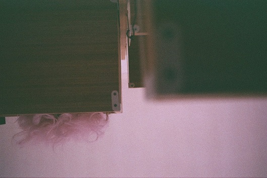 Une perruque posée sur des meubles au mur vu du dessous